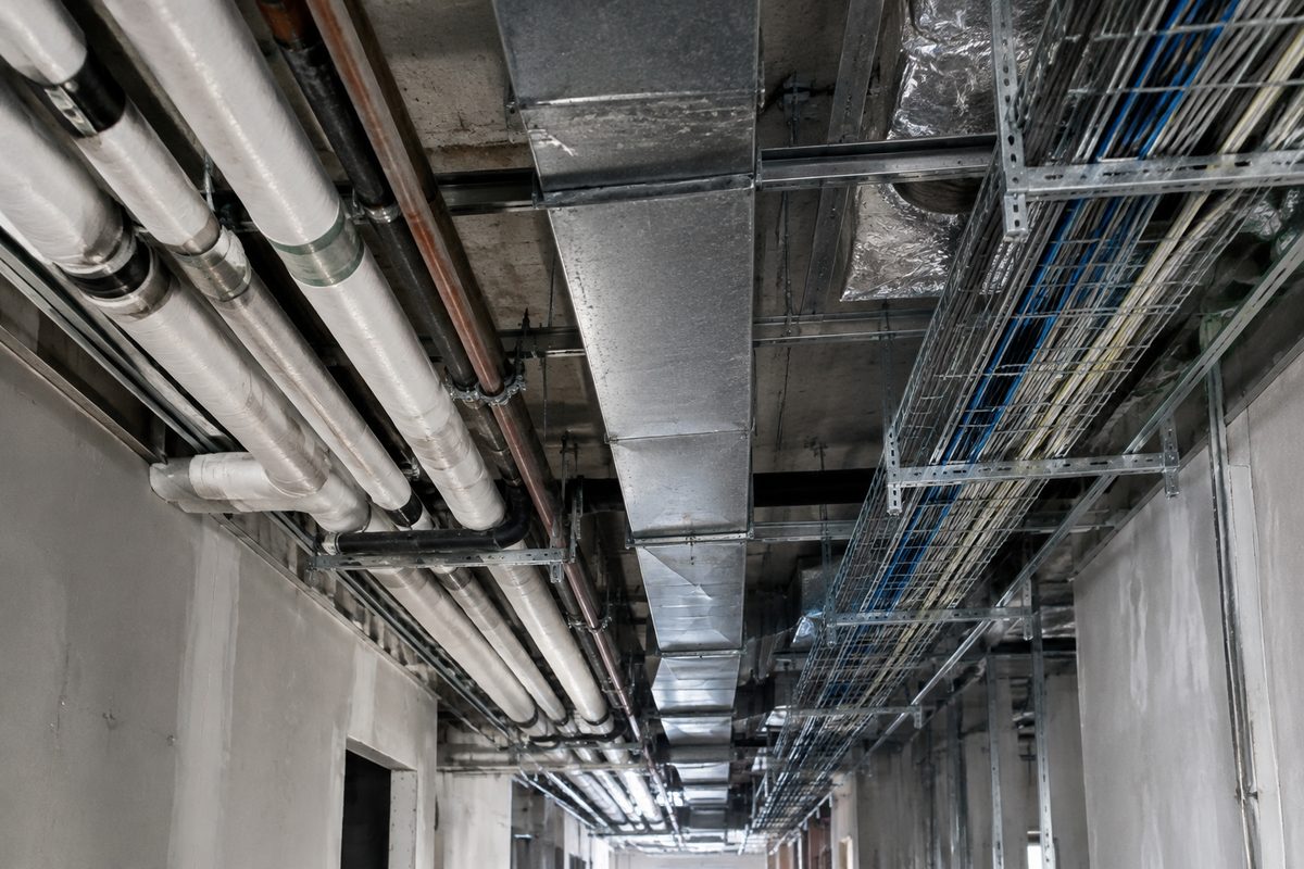 Pipework, ductwork and cable trays above an open corridor ceiling
